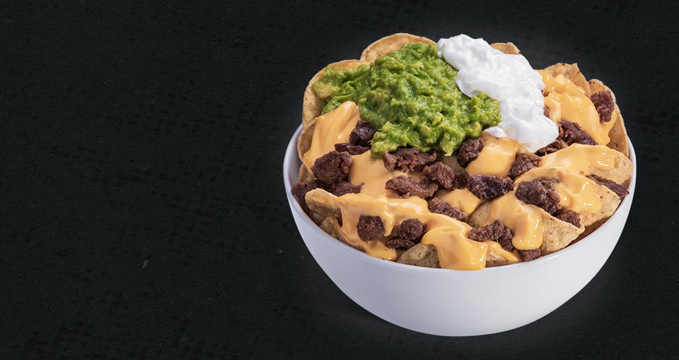 Super Nachos - Nachos in bowl with cheese, meat, sour cream and smashed avocado